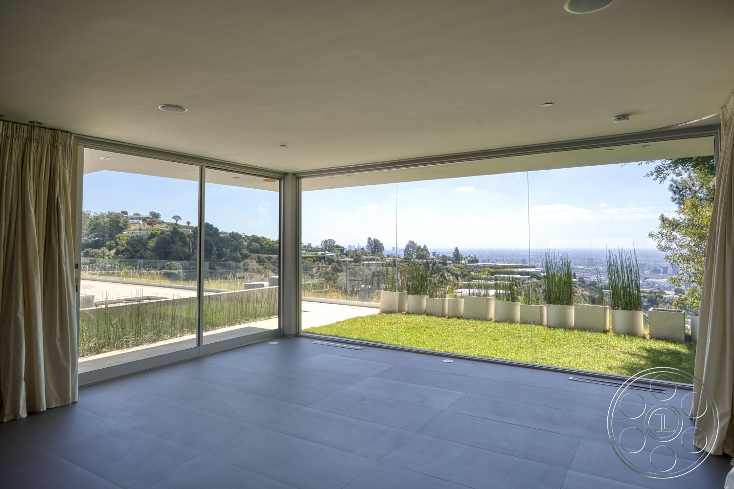 Modern 525 - minimalist design, concrete flooring, floor-to-ceiling windows, sliding glass door, urban skyline view, open living space, contemporary architectural style, green grass landscaping, modern curtain drapes