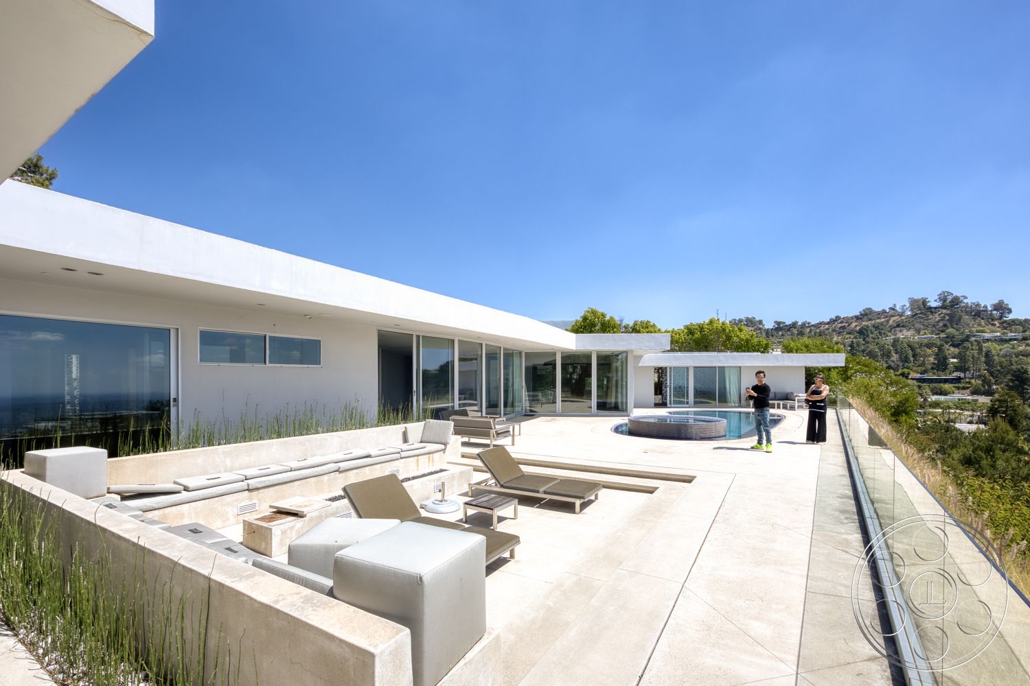 Modern 525 - exterior, white stucco walls, glass railing, rectangular swimming pool, floor-to-ceiling windows, flat roof design, concrete patio flooring, modern outdoor seating area, open hillside view, landscaped grass border