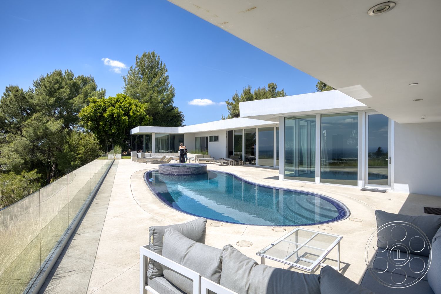 Modern 525 - exterior, flat roof, open floor plan, glass sliding doors, floor-to-ceiling windows, modern architectural style, clear glass railing, infinity pool, wooden lounge chairs, concrete patio flooring, landscaped garden setting, curved pool border