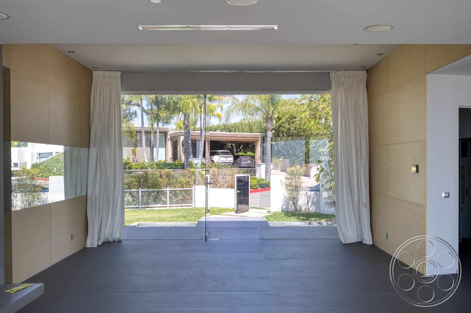Modern 525 - natural light, minimalist design, large glass sliding doors, open floor plan, curtains, landscape view, modern architectural style, palm tree view, wood paneling accent wall, dark tile floor