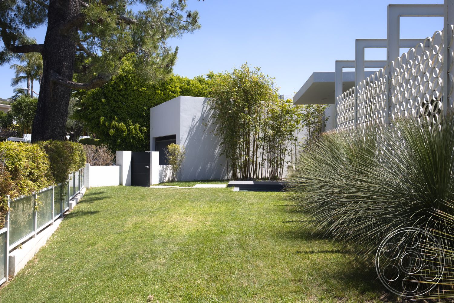 Modern 525 - exterior, flat roof, minimalist style, urban setting, landscaped lawn, dark wood door, white concrete walls, bamboo landscaping, modern architectural design, geometric concrete screen wall, glass fence panels, grassy garden area