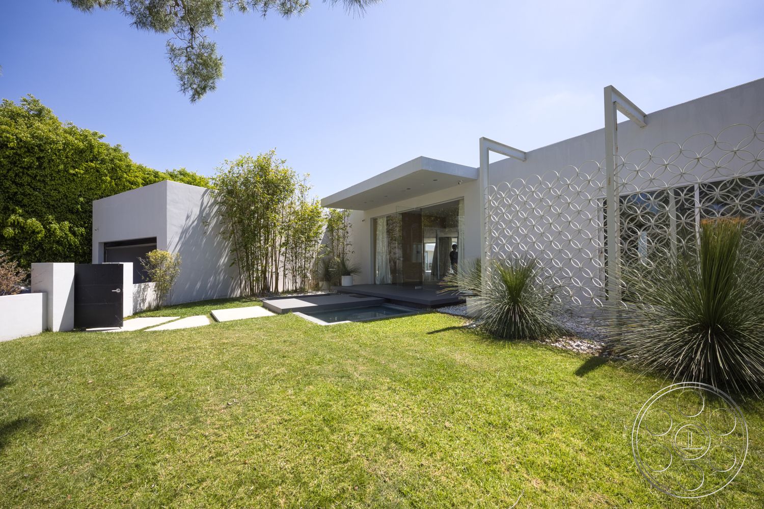 Modern 525 - exterior, concrete pathway, concrete steps, large floor-to-ceiling windows, flat roof design, rectangular garden layout, minimalist architectural style, modern residential design, smooth white stucco walls, landscaped garden with grasses, metal geometric screen, dark wood entrance door, greenery and plants surrounding home