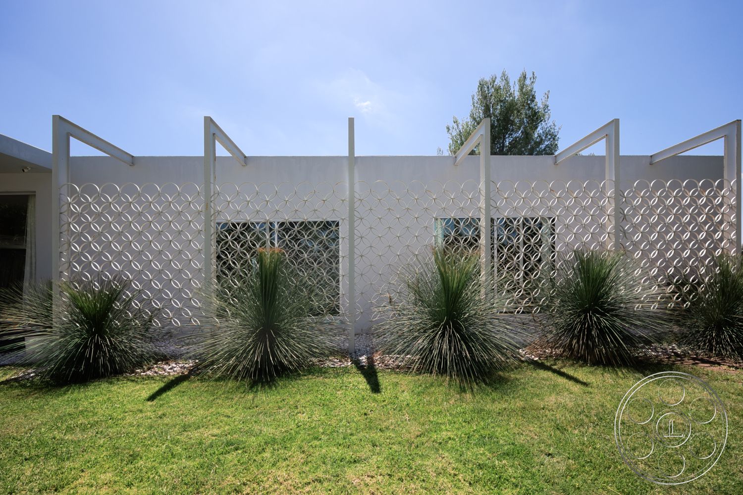 Modern 525 - exterior, modern architectural style, landscaped garden area, white concrete wall, decorative aluminum trellis, geometric pattern screen, low-water use grasses, rock mulch ground cover, clear view windows
