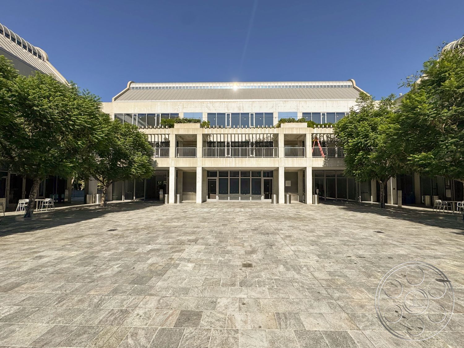 Museum 2 - exterior, floor-to-ceiling windows, modern architectural style, landscaped trees, granite plaza flooring, rectangular building shape, balcony railings, concrete building structure, open courtyard area
