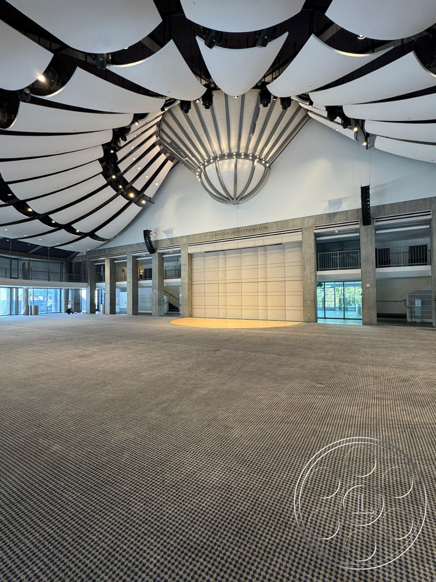 Museum 2 - neutral color palette, glass wall features, textured carpet flooring, modern chandelier lighting, open interior layout, suspended ceiling design, multi-purpose performance space, exterior auditorium structure, industrial concrete columns, vaulted ceiling with acoustic panels