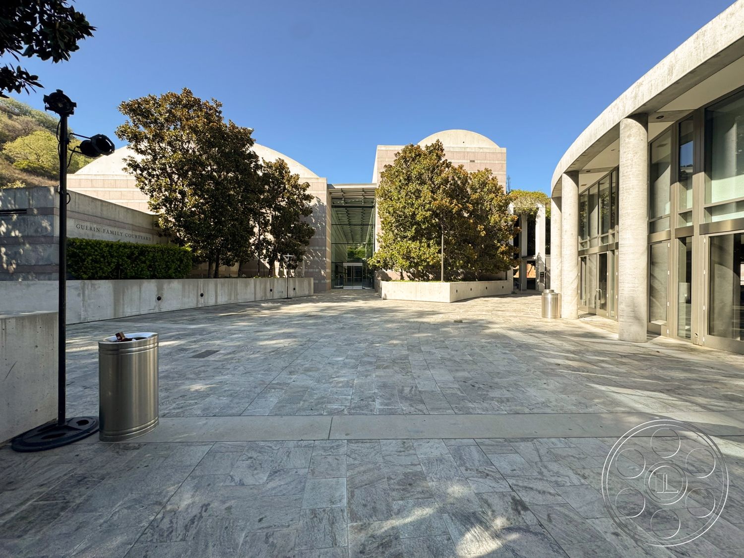 Museum 2 - exterior, outdoor seating area, concrete walls, modern architectural style, polished stone flooring, floor-to-ceiling glass windows, landscaped courtyard setting, concrete planter boxes, sculptural light fixtures, curved concrete edges, large canopy trees