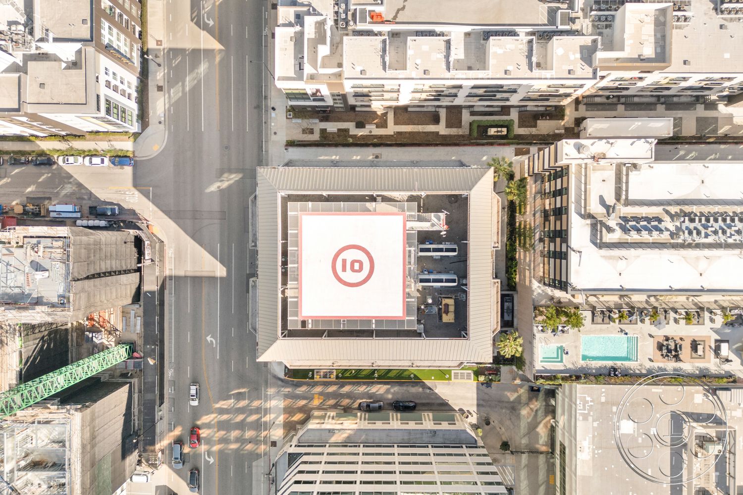 Rooftop-52 - exterior, paved driveway, street view, modern architectural style, flat rooftop design, green landscaping elements, surrounding urban landscape, pool area with lounge chairs, concrete rooftop helipad, adjacent glass-clad buildings