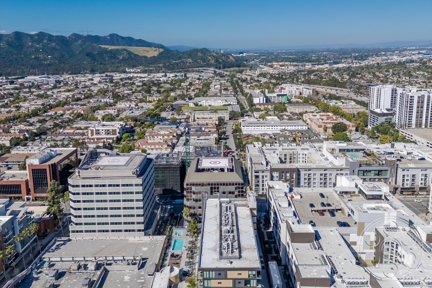 Rooftop-52 - exterior, metal railings, urban landscape, multi-story commercial buildings, concrete office building exteriors, glass window facades, flat roof structures, aerial city view, surrounding residential neighborhoods, green park spaces, hillside backdrop, asphalt parking lots
