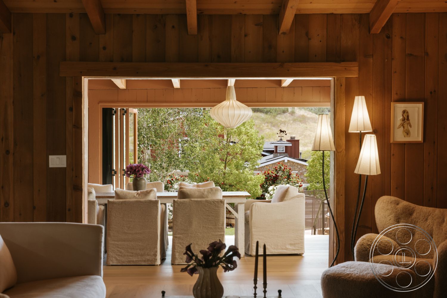 Modern-Farmhouse 20 - natural light, contemporary design, open floor plan, cozy seating area, upholstered dining chairs, glass sliding doors, hardwood floor, exposed wood ceiling beams, minimalist pendant lighting, textured fabric sofa, wood paneling walls, view of landscaped garden, decorative floor lamps, rabbit ear pendant light