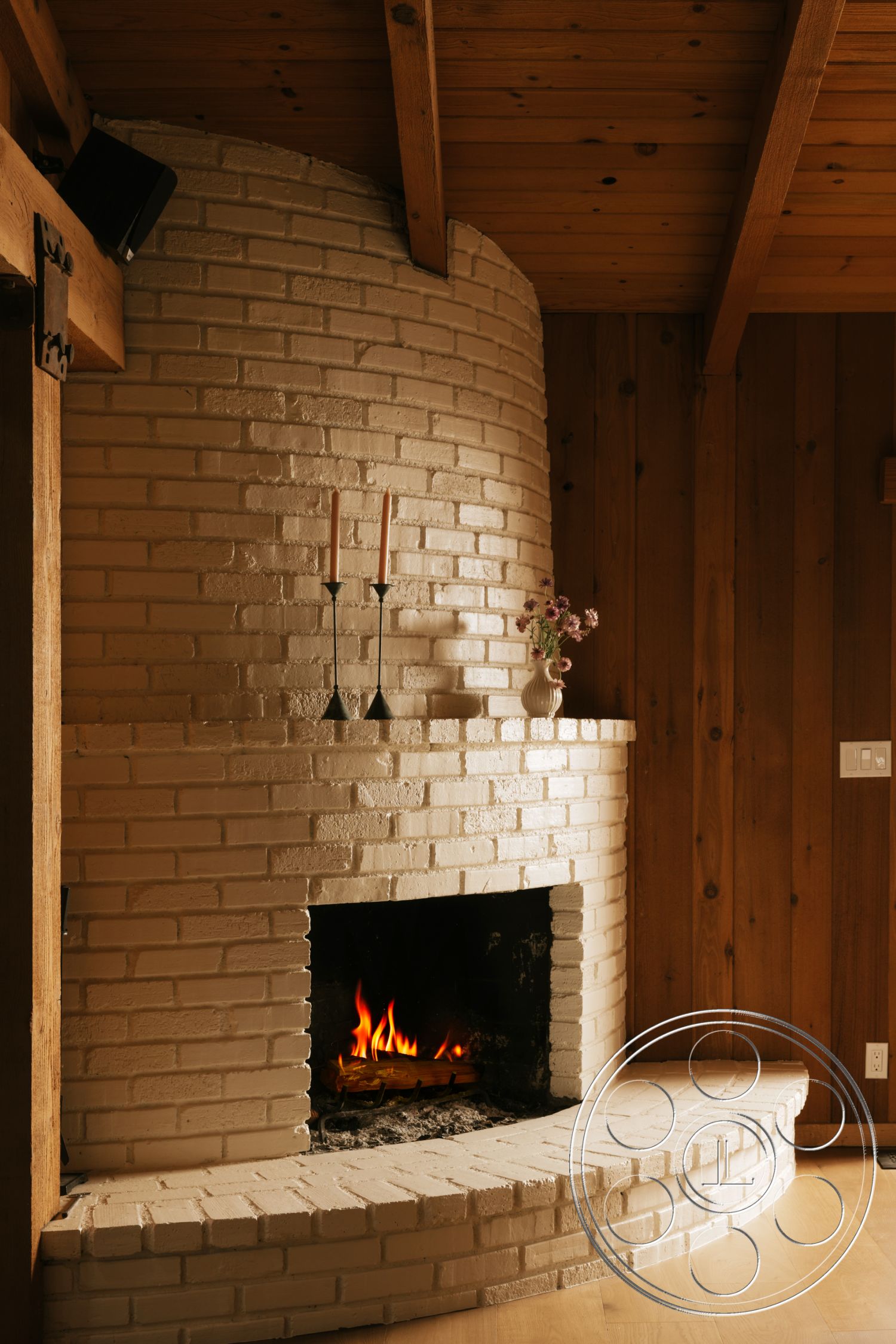 Modern-Farmhouse 20 - minimalist decor, natural wood accents, wood beam ceiling, contemporary rustic style, dark wood wall paneling, white brick fireplace surround, curved fireplace hearth, floor-to-ceiling fireplace, candles on mantel