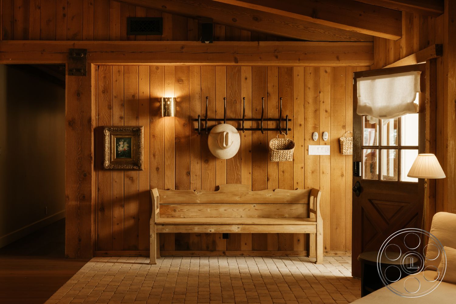 Modern-Farmhouse 20 - framed artwork, woven baskets, decorative wall sconce, farmhouse style, neutral color scheme, exposed wood ceiling beams, wood paneling walls, glass door with wooden frame, planked wood flooring, wood bench seat, black metal wall hooks