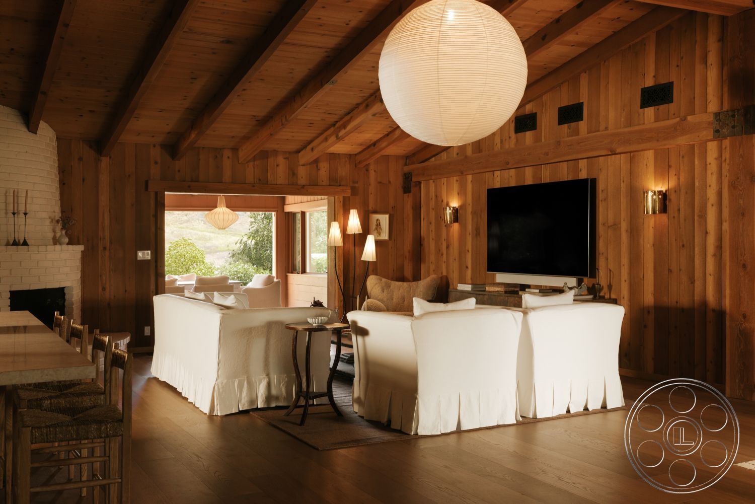 Modern-Farmhouse 20 - textured area rug, cozy seating area, modern pendant lighting, open concept living space, exposed wood ceiling beams, hardwood living room floors, wood paneling walls, rustic decor accents, white painted fireplace, flat screen television mount, large windows with nature views, neutral colored furniture, wooden dining bar stools