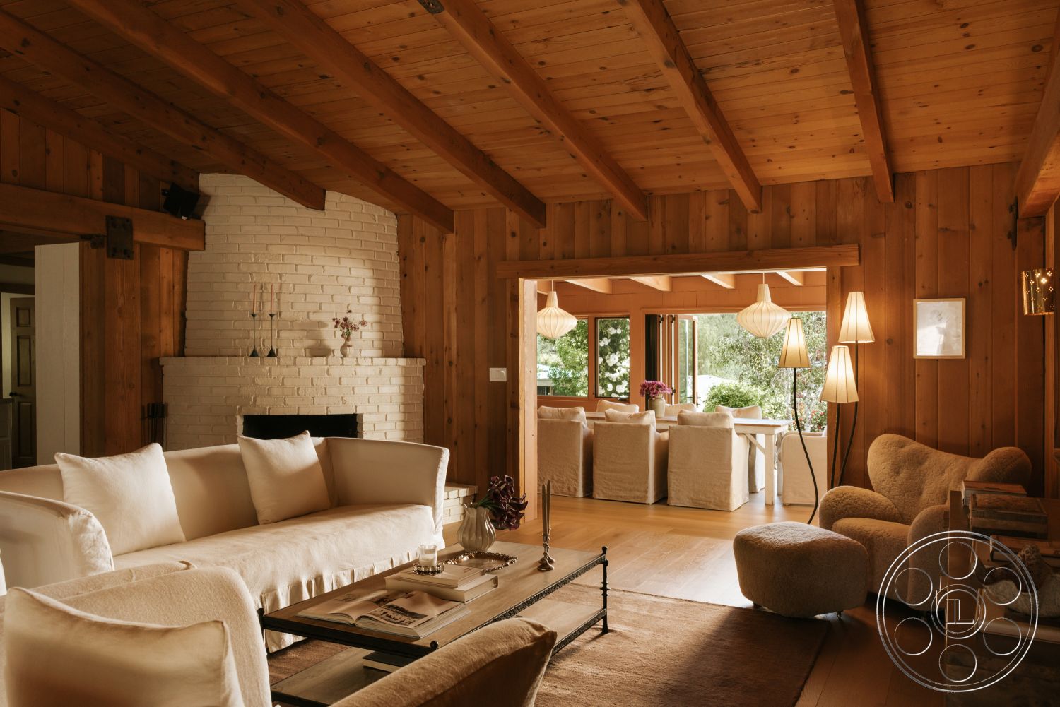 Modern-Farmhouse 20 - neutral color palette, plush fabric sofa, contemporary light fixtures, exposed wood ceiling beams, hardwood living room floors, open floor plan layout, wood paneling walls, mid-century modern interior, glass windows with garden view, white painted brick fireplace