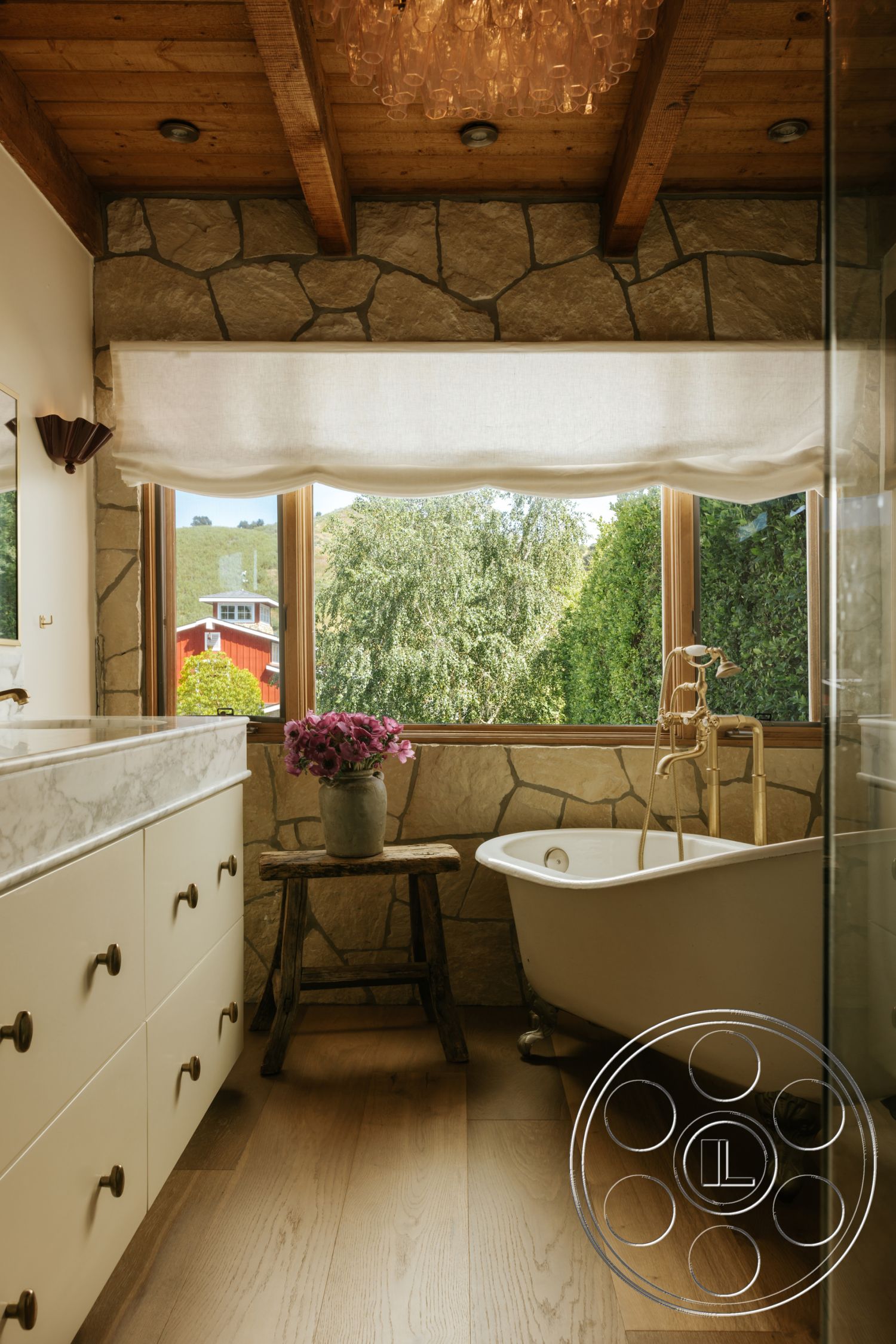 Modern-Farmhouse 20 - floor-to-ceiling windows, stone feature wall, wood beam ceiling, modern faucet fixtures, marble bathroom countertop, rustic wooden side table, hardwood bathroom floors, freestanding clawfoot bathtub