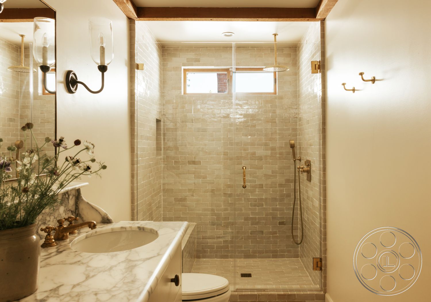 Modern-Farmhouse 20 - glass shower enclosure, ceramic tile flooring, gold faucet fixtures, light wood ceiling beams, built-in shower niche, white painted walls, modern wall sconces, marble bathroom countertop, framed window, stone shower walls
