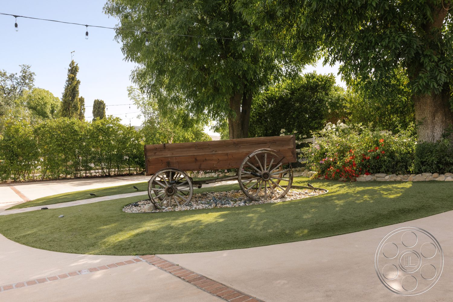 Modern-Farmhouse 20 - exterior, lush greenery, flowering shrubs, paved walkway, concrete driveway, natural stone landscaping, landscape planting beds, decorative gravel border, wooden wagon feature, green artificial turf, brick inlay details