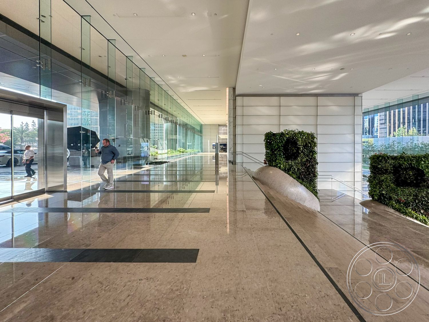 Ave Of The Stars - minimalist design, open space, modern architectural style, polished marble flooring, green wall feature, glass wall panels, fluorescent ceiling lighting, rectangular lobby layout, stone seating element, large entrance with glass doors