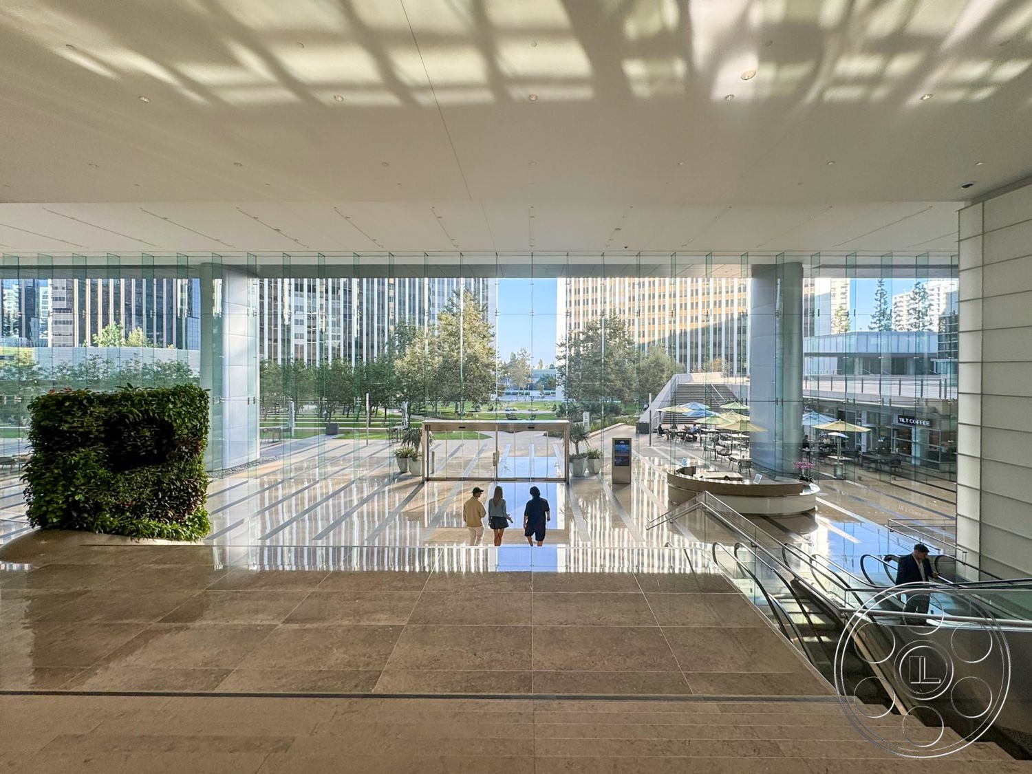 Ave Of The Stars - bright natural light, floor-to-ceiling windows, glass facade, polished marble flooring, modern seating area, green living wall, contemporary architectural style, open atrium space, structured landscaping, stainless steel escalators, urban park view