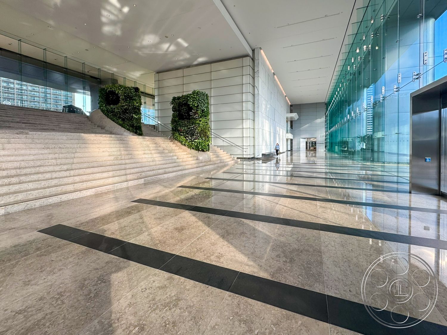 Ave Of The Stars - natural light, floor-to-ceiling glass, modern architectural style, polished marble flooring, glass wall partitions, indoor plant accents, minimalist wall design, black stone inlay flooring, exposed stone stairs, vertical garden feature, bright open lobby, elevators with glass doors
