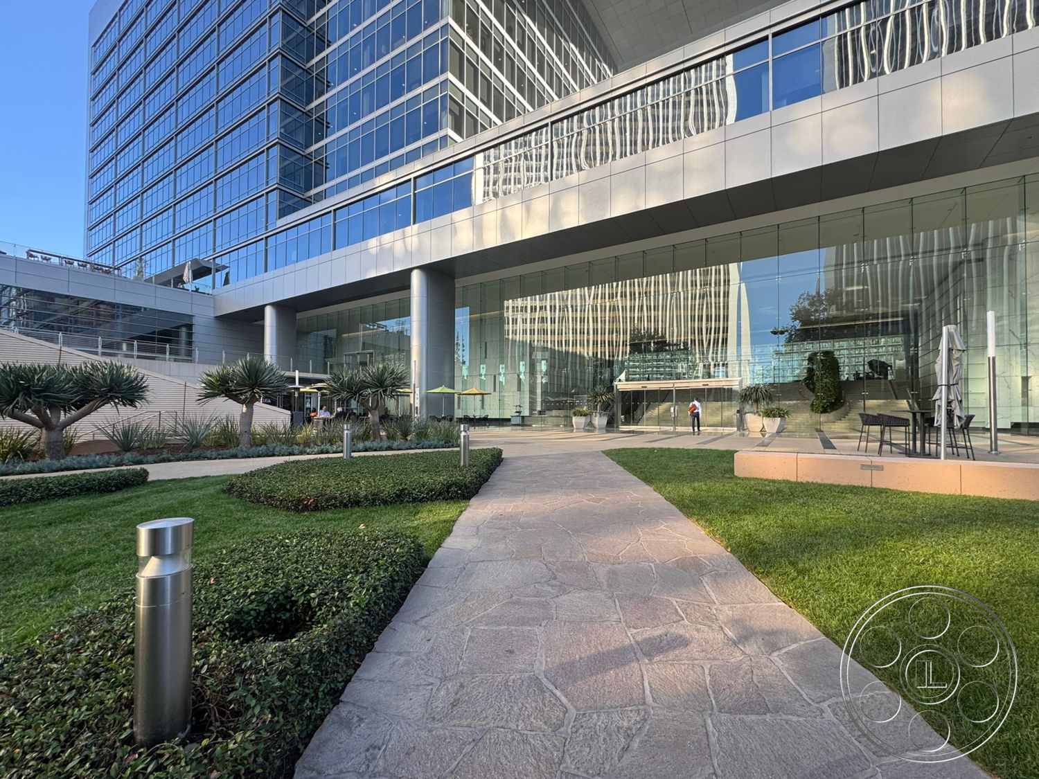 Ave Of The Stars - exterior, floor-to-ceiling windows, rectangular planters, concrete walkway, green grass lawn, glass curtain wall facade, landscaped garden with shrubs, steel and glass structural elements, open courtyard area, modern office building, polished stone entryway, stainless steel light fixtures