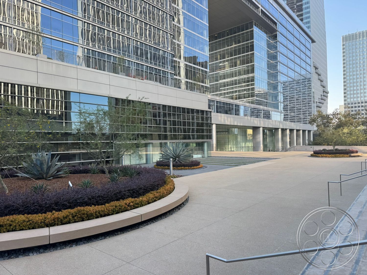 Ave Of The Stars - exterior, green foliage, urban environment, steel railing, landscaped garden area, modern architectural design, glass curtain wall facade, textured concrete pavers, concrete plaza flooring, rounded concrete planter beds