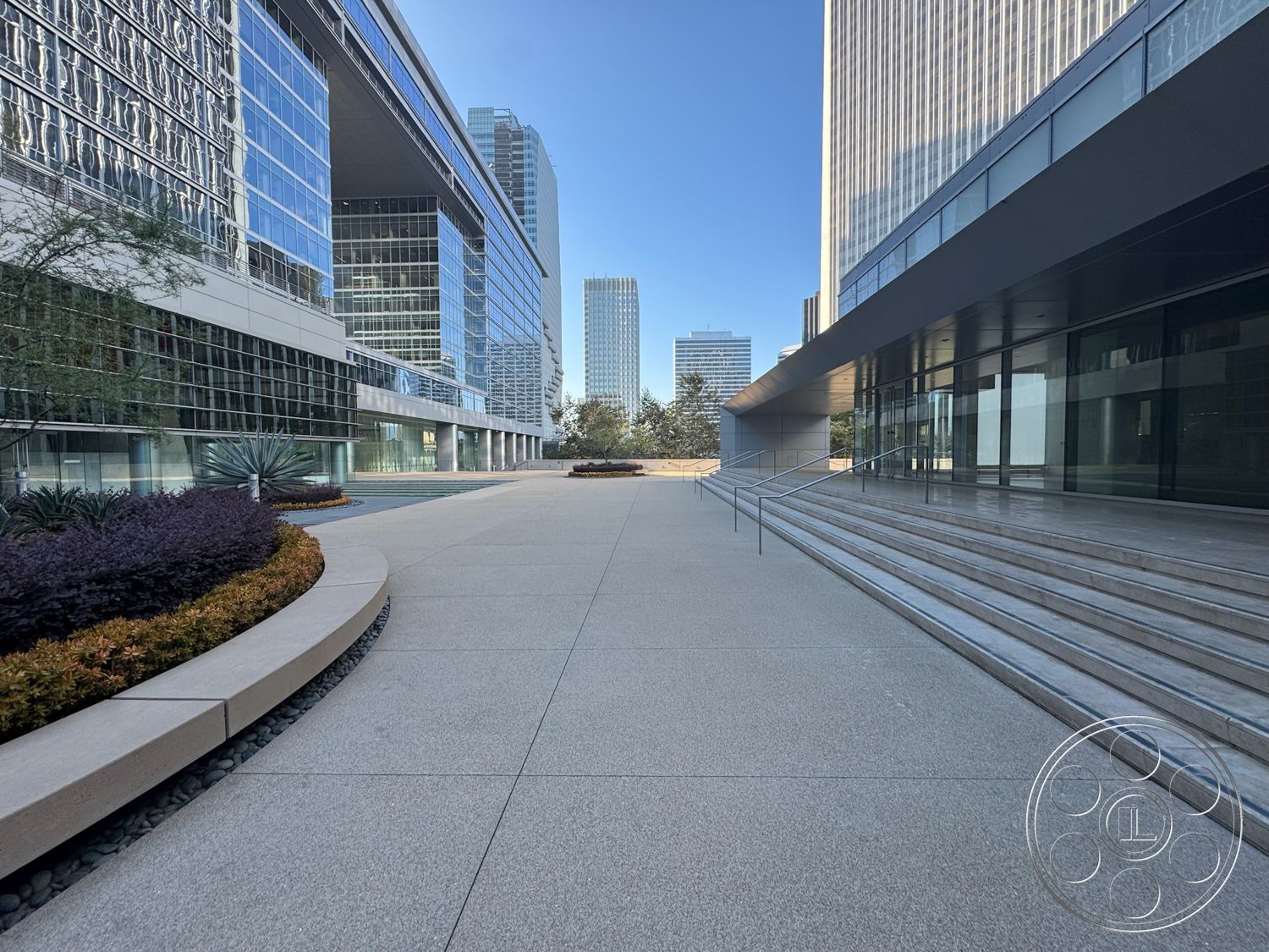 Ave Of The Stars - exterior, urban setting, modern architectural style, commercial building entrance, polished concrete plaza flooring, glass curtain wall, rectangular walkway, landscape planters with shrubs, landscape rocks around planting beds, linear concrete steps with metal railings, curved landscape border