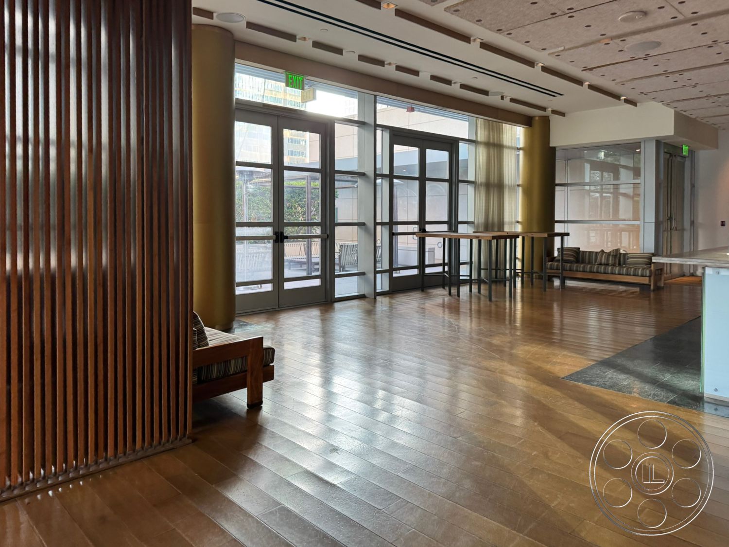Ave Of The Stars - neutral color palette, hardwood flooring, open layout, modern furniture, floor-to-ceiling windows, bright natural lighting, glass entrance doors, vertical wood slat wall, textures plaster ceiling, striped upholstery sofa, tall tables