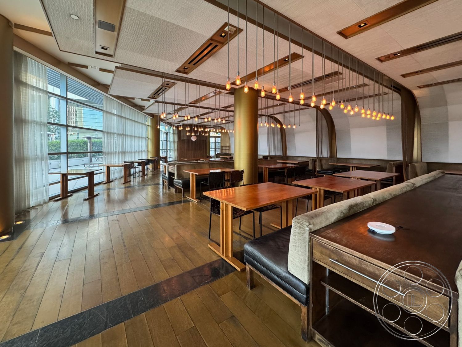 Ave Of The Stars - minimalist decor, natural light, open floor plan, soft drapery, modern industrial design, glass curtain wall, textured ceiling panels, black leather dining chairs, hardwood restaurant flooring, rectangular wooden dining tables, metal framed seating, exposed light bulb pendant lighting, golden column accents, fabric upholstered bench seating, wooden restaurant bar counter