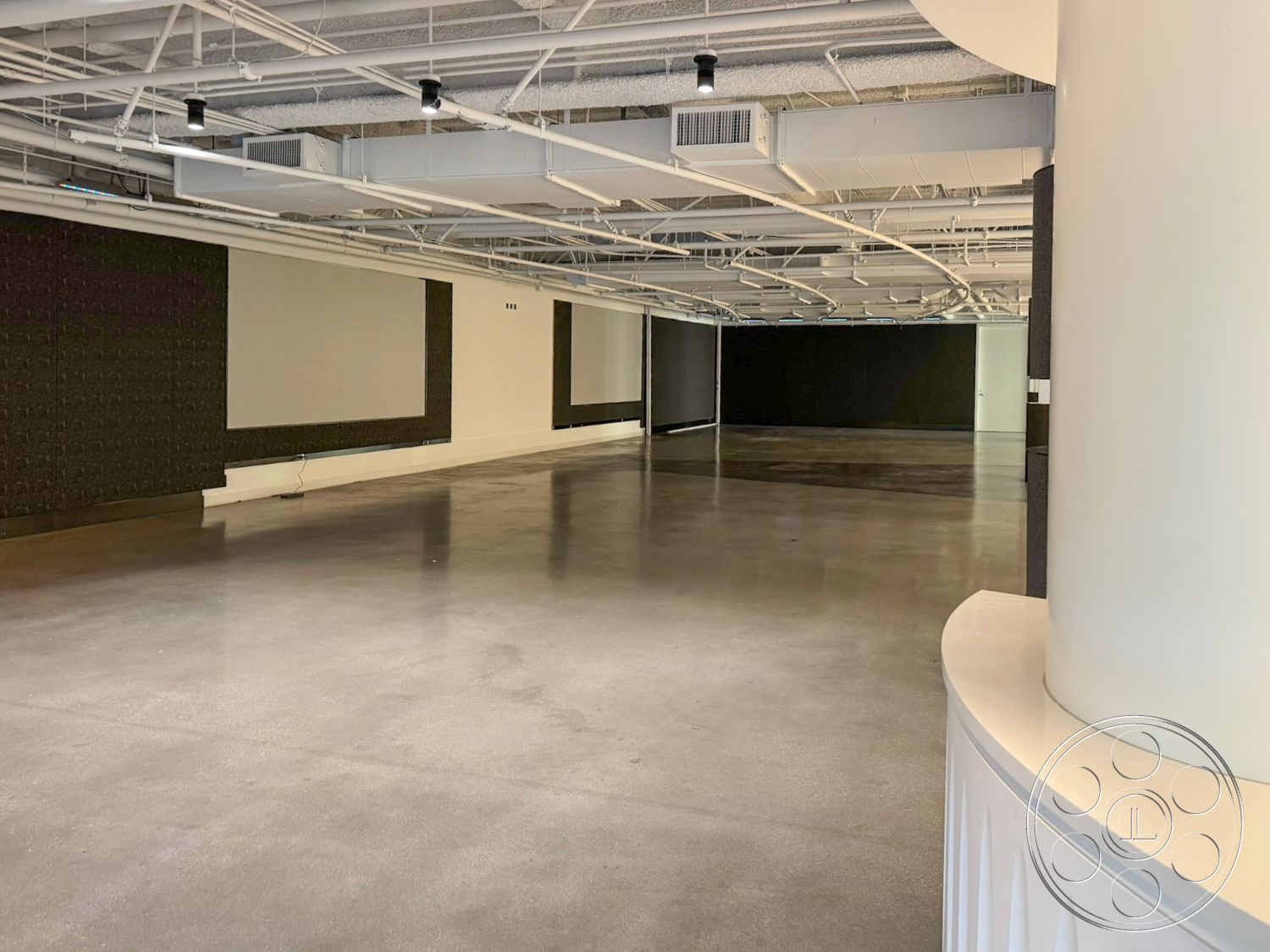 Ave Of The Stars - interior space, black accent wall, industrial style architecture, exposed concrete flooring, white cylindrical column, modern ceiling with exposed ductwork