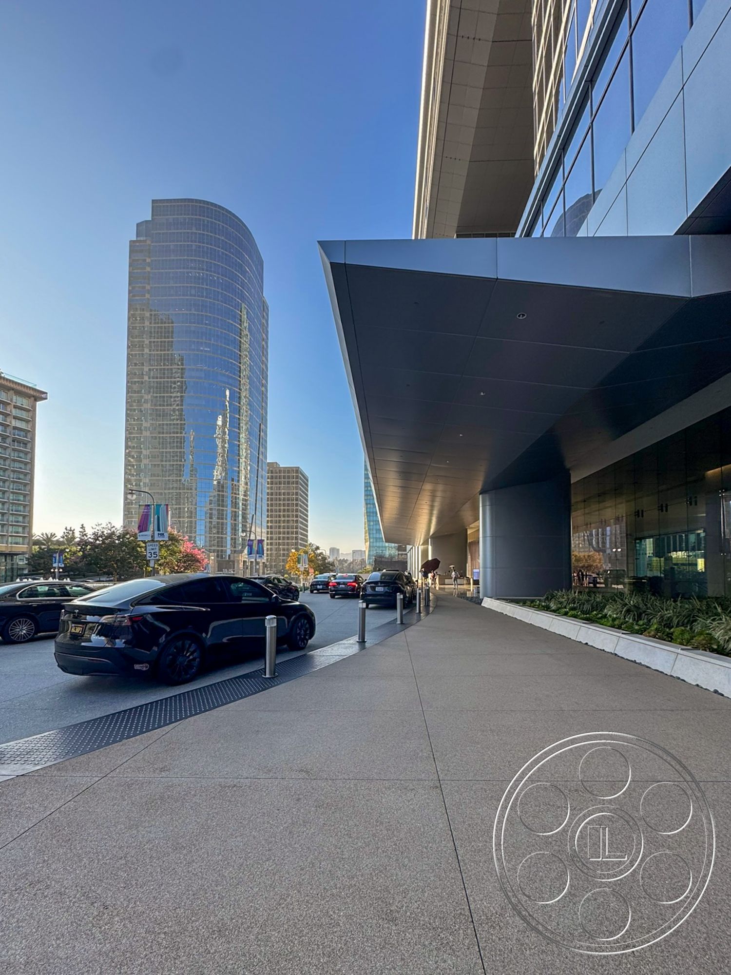 Ave Of The Stars - exterior, modern architectural style, polished stone accents, landscaped outdoor area, glass building facade, textured concrete sidewalk, metal overhang, curved skyscraper shape, reflected city skyline, parking area with cars
