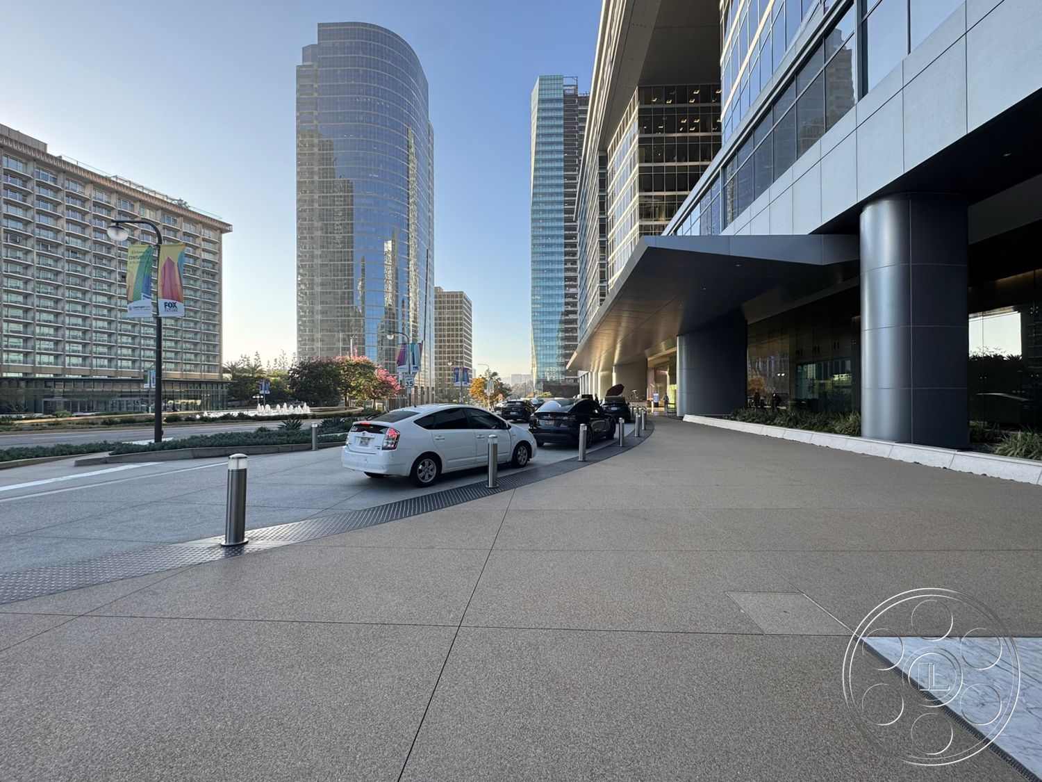 Ave Of The Stars - exterior, landscaped gardens, outdoor seating area, urban landscape setting, steel column supports, curved building shape, glass curtain wall façade, modern high-rise architecture, polished concrete driveway, paved pedestrian walkway, reflected glass windows, street-level parking area, decorative street lamps