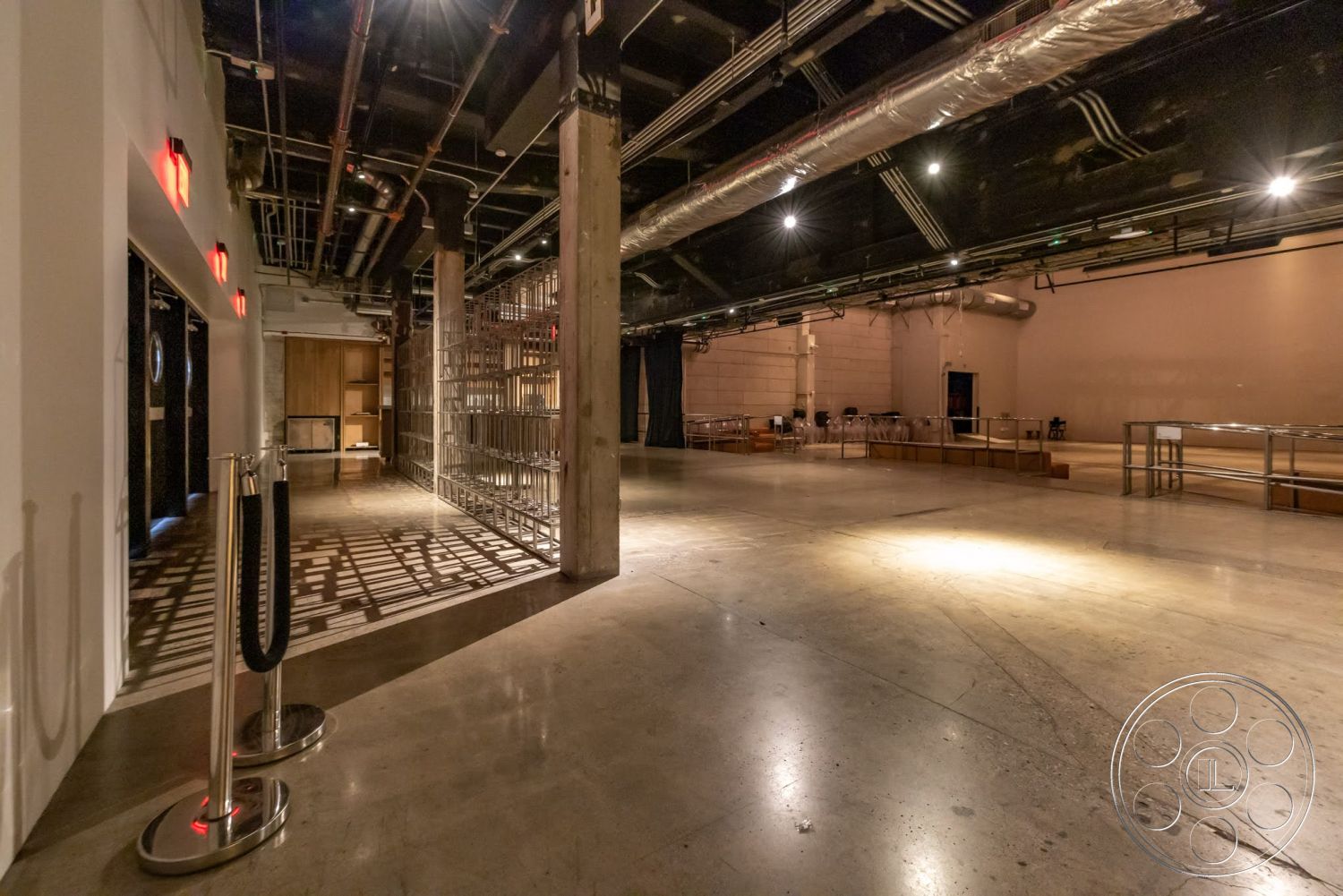 Sunset Campus - open space layout, high ceiling, industrial lighting fixtures, modern architectural design, glass partition wall, exposed concrete flooring, interior event space, wooden structural columns, metal overhead ducts, backstage area access