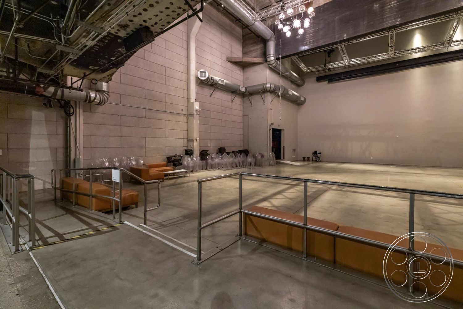 Sunset Campus - neutral color palette, recessed lighting, modern design, concrete floor, open space layout, textured concrete walls, metal railing, high ceiling, industrial lighting, exposed ductwork, modular seating, metal support beams, glass chairs