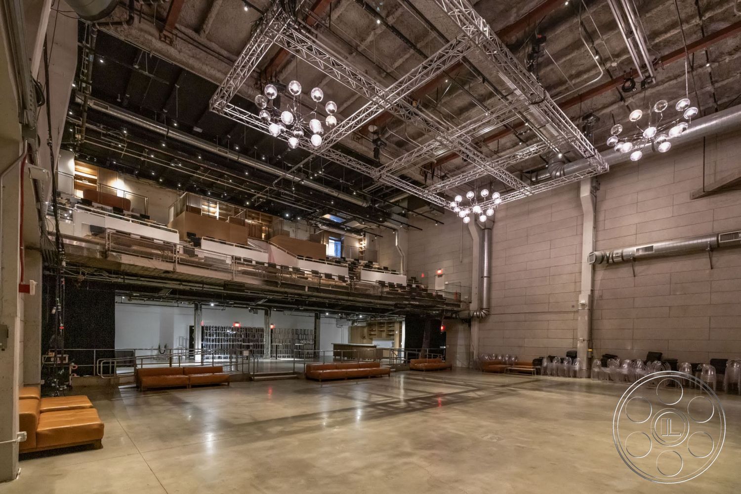 Sunset Campus - open floor plan, concrete flooring, exposed concrete walls, track lighting fixtures, wooden seating area, glass balcony railings, performance space interior, metal ceiling grid, industrial-style loft, sound booth