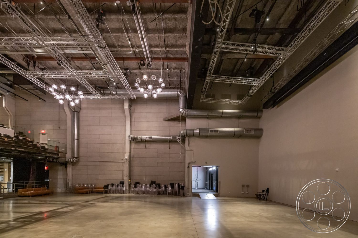 Sunset Campus - high ceilings, large windows, open floor plan, concrete flooring, industrial lighting fixtures, metal ductwork, exposed steel ceiling beams, gray concrete block walls, events space interior