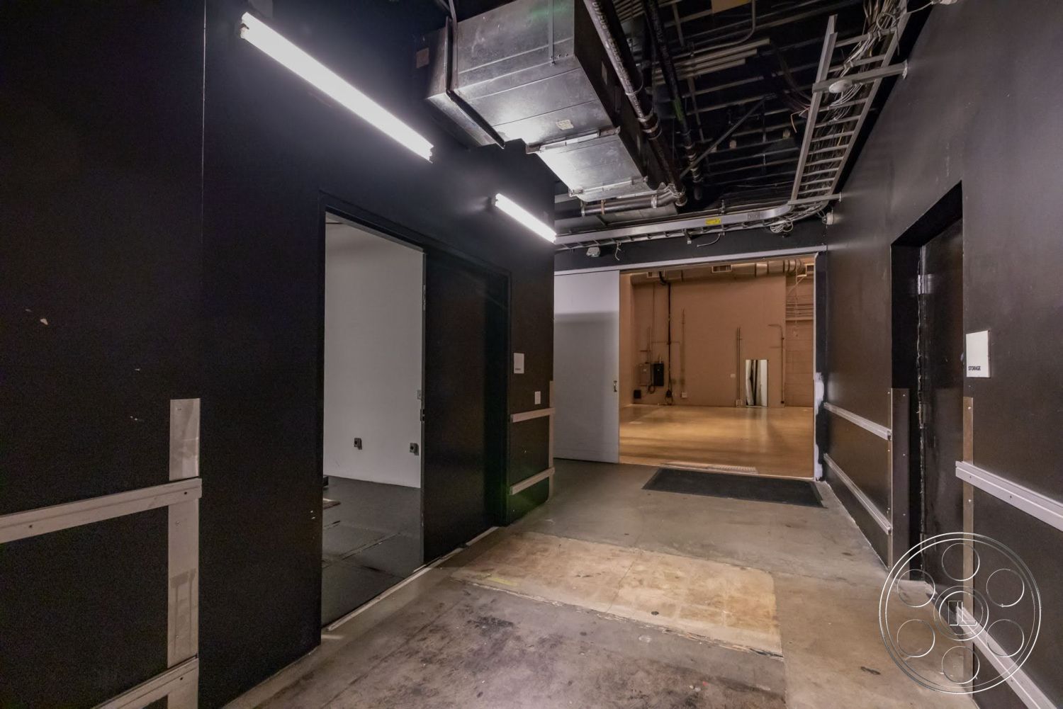 Sunset Campus - concrete flooring, open space layout, industrial lighting fixtures, exposed ductwork, black painted walls, interior corridor, rectangular doorways, modern utility design