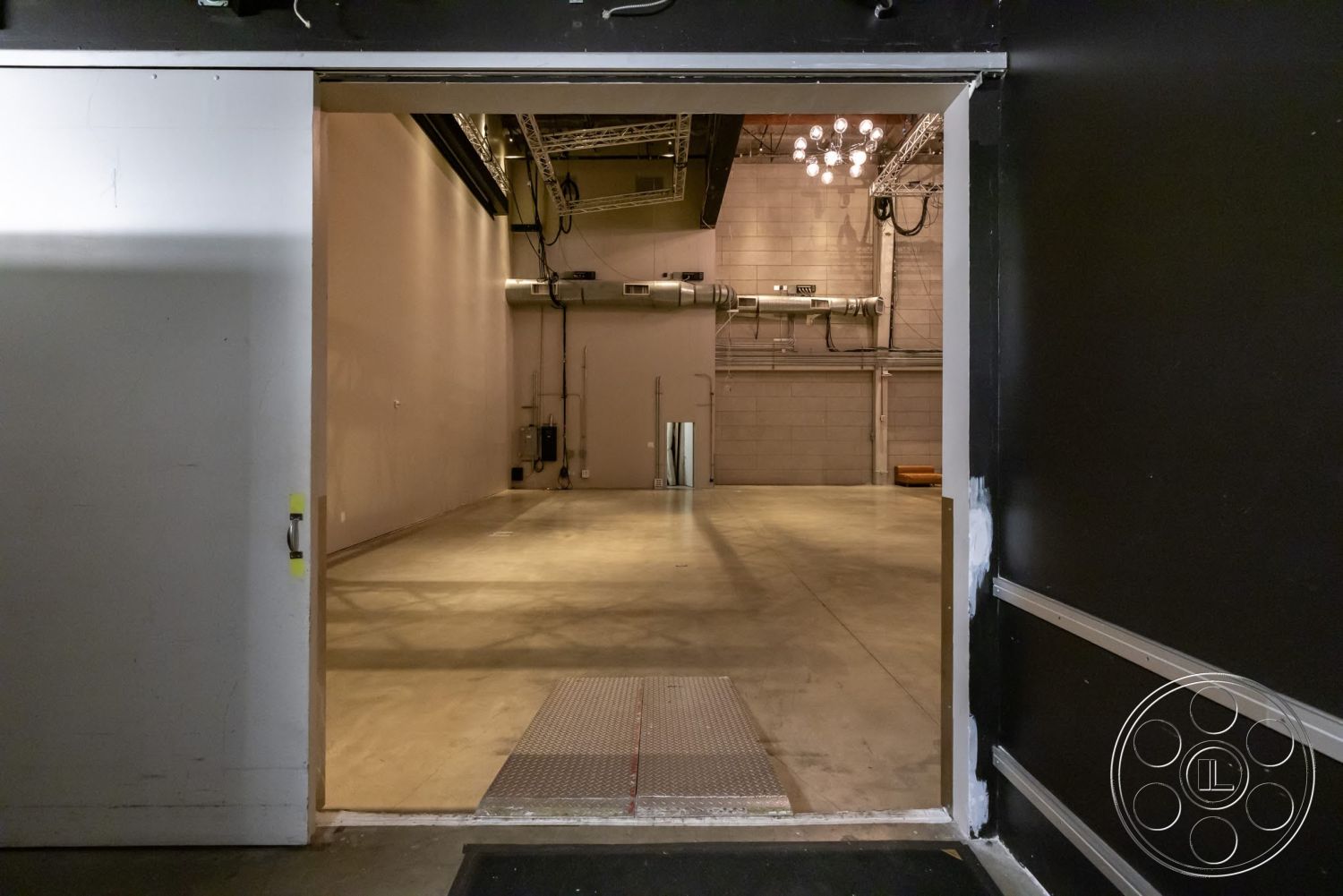 Sunset Campus - high ceilings, open layout, concrete flooring, industrial lighting, exposed ductwork, steel support beams, light gray painted walls, aluminum door frame, steel grating entrance mat
