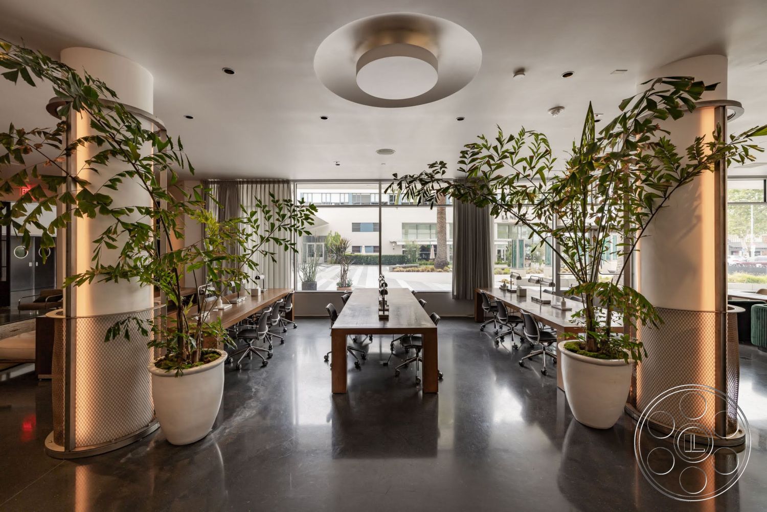 Sunset Campus - polished concrete floor, open layout, floor-to-ceiling windows, curtain drapery, modern minimalist design, white ceiling with recessed lighting, large rectangular conference table, leather office chairs, plant-filled white planters, textured metal column wraps, soft natural light environment