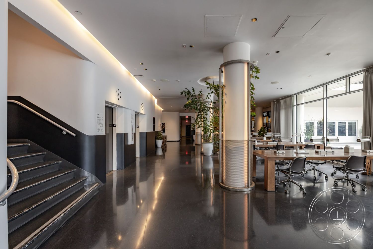 Sunset Campus - exterior, surrounding greenery, textured wall paneling, large potted plants, grey painted walls, recessed ceiling lighting, elevator access area, glass window wall, glossy black tile flooring, modern steel stair railing, laminated wood conference table, round concrete column, office workspace layout