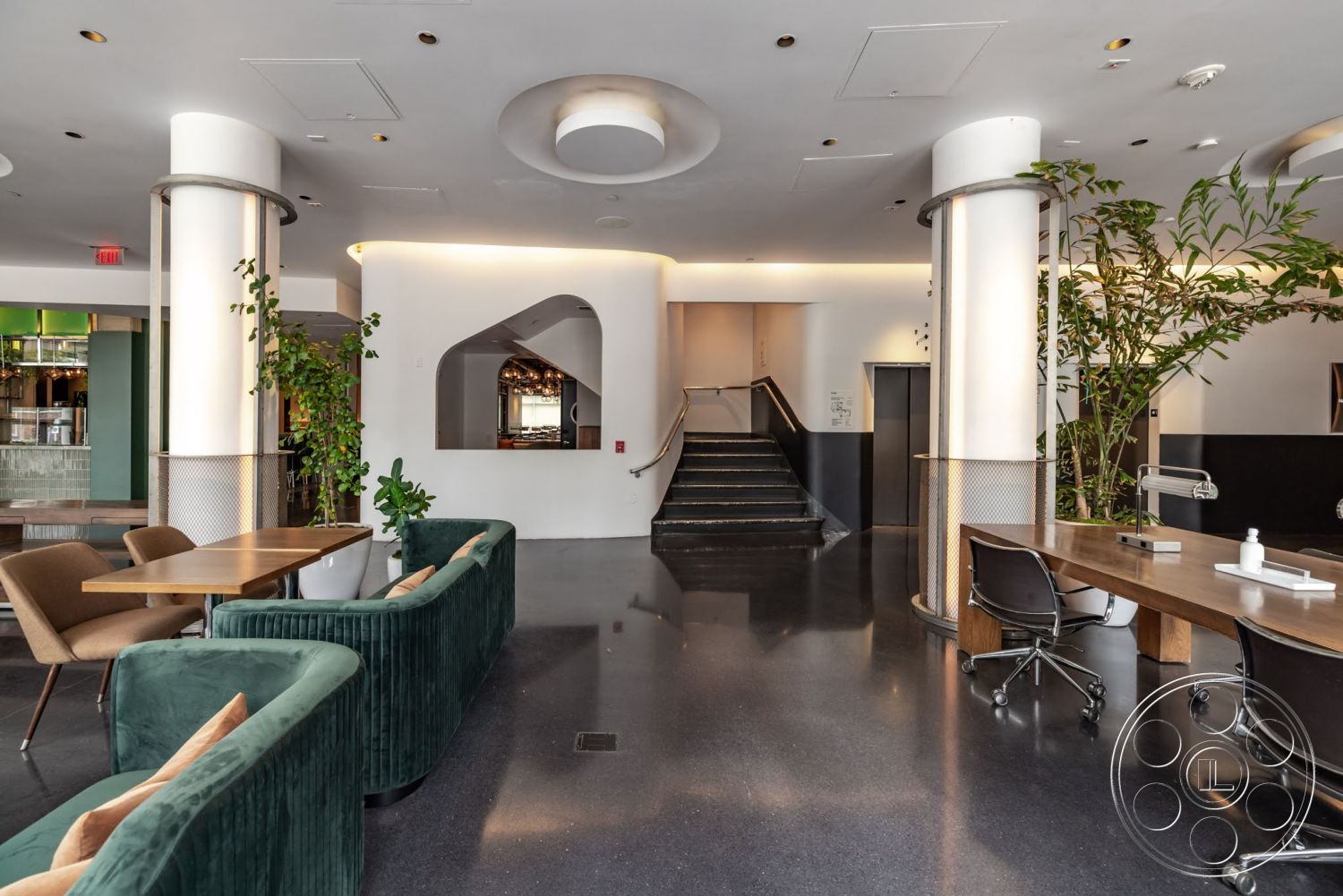 Sunset Campus - minimalist decor, open floor plan, polished concrete flooring, wooden dining table, modern aesthetic, floor-to-ceiling windows, green indoor plants, pendant lighting fixtures, wall-mounted mirrors, upholstered lounge chairs, curved velvet sofas, metal accent columns, staircase with black treads, continuous lighting strip