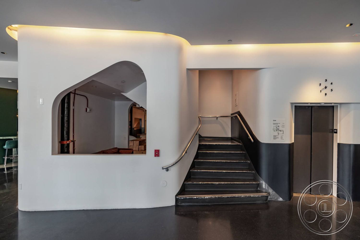 Sunset Campus - exterior, floor-to-ceiling windows, white plaster walls, black accent wall, minimalist architectural style, concrete staircase, curved stair railing, high-gloss concrete floor, modern wall lighting, arched wall opening, interior lobby setting