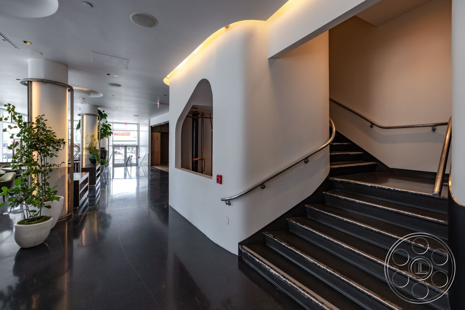 Sunset Campus - minimalist design elements, floor-to-ceiling windows, soft ambient lighting, architectural planters, modern stair railing, polished black concrete floors, curved white walls, exposed column bases, geometry of cut-out archway