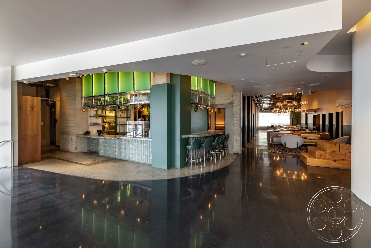 Sunset Campus - minimalist design, plant decor, open floor plan, polished concrete flooring, modern lighting fixtures, exposed concrete walls, wooden accent wall, large windows with natural light, curved bar counter, glass tile backsplash, green glass light fixtures, brushed metal bar stools, restaurant lobby area, seating area with upholstered furniture