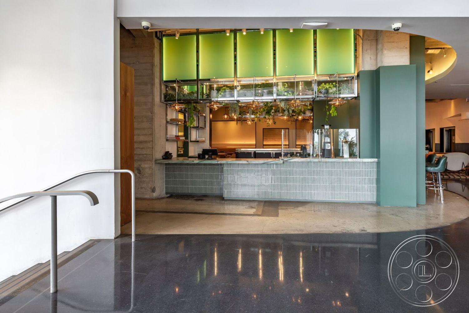 Sunset Campus - polished concrete flooring, modern pendant lighting, minimalist style, exposed concrete walls, metal shelving units, wood accent wall, open layout design, green glass wall panels, tiled reception counter, hanging plant decor, curved bar seating, architectural detailing in ceiling