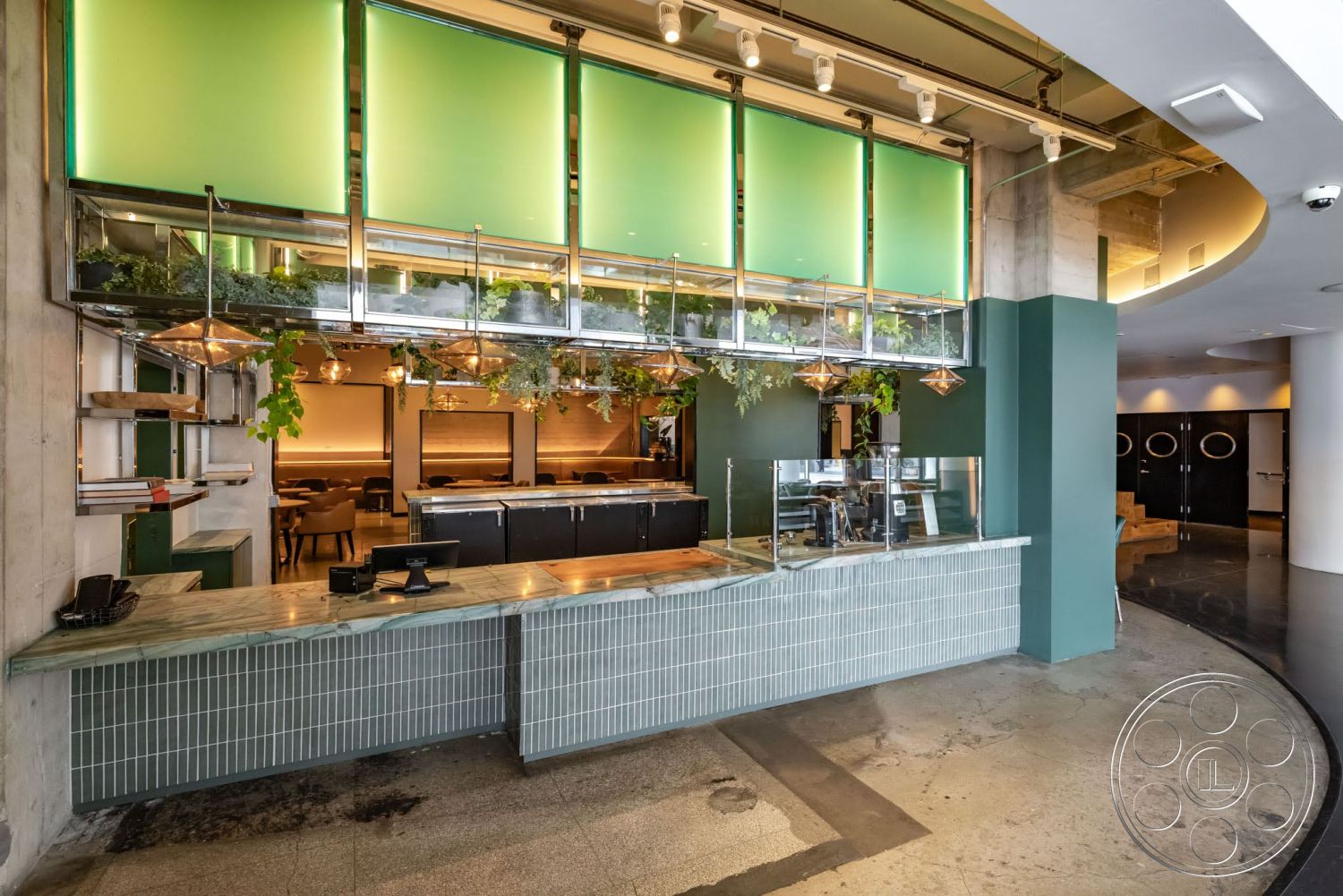 Sunset Campus - ambient lighting, exposed concrete walls, marble countertop, dark wood accents, textured plaster walls, hanging pendant lights, curved room layout, glossy tile bar front, open shelving with metal support, green glass panel partition, sprouting indoor plants, modern café environment