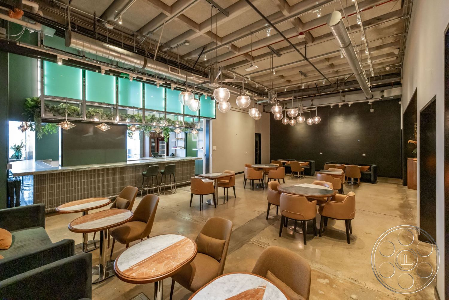Sunset Campus - open floor plan, black accent wall, modern bar area, leather dining chairs, glass wall panels, industrial-style interior, exposed concrete flooring, pendant light fixtures, steel ceiling beams, marble table tops, green wall planters