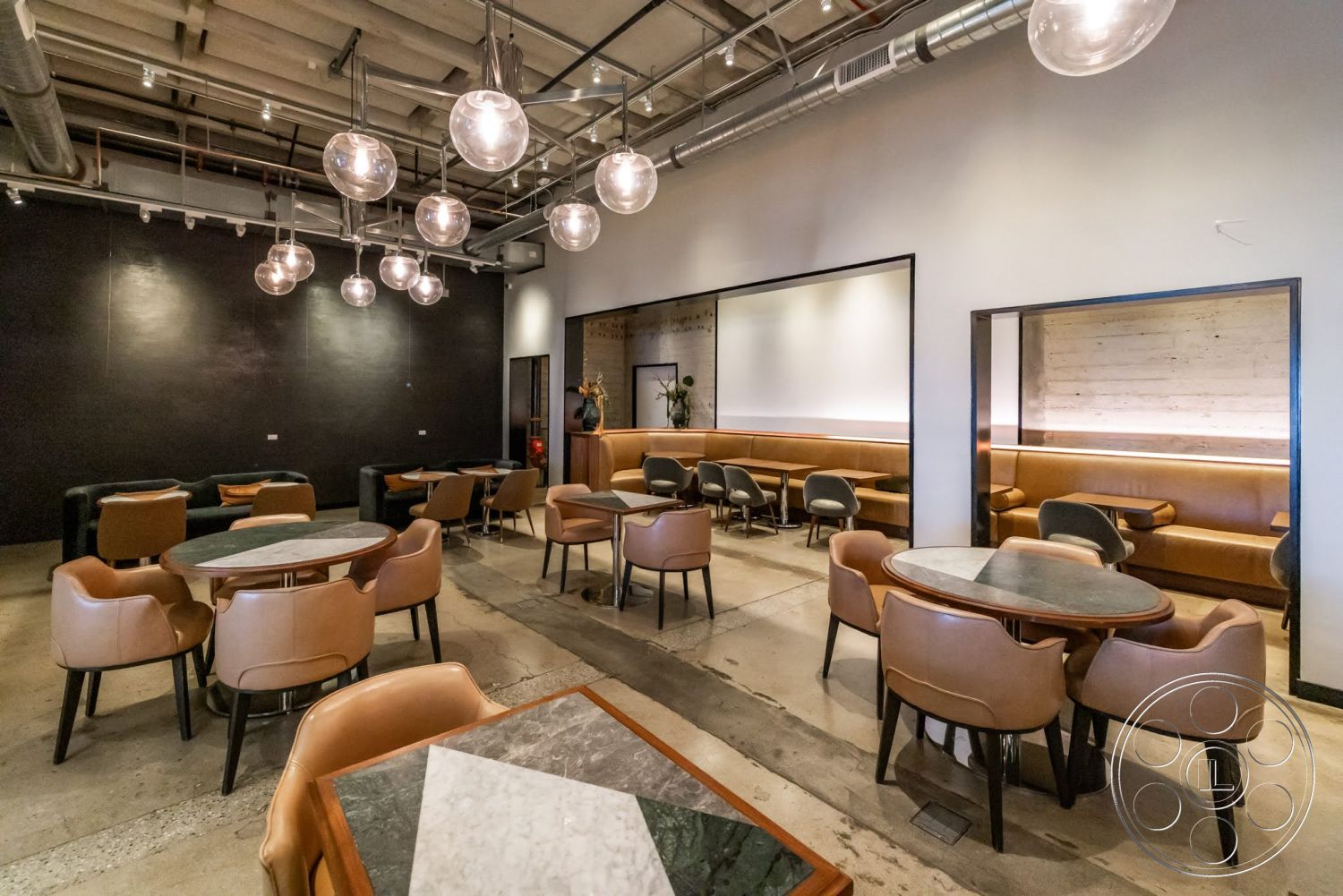 Sunset Campus - contemporary style, soft ambient lighting, glass pendant lighting, exposed concrete flooring, open layout space, dark painted accent wall, leather upholstered dining chairs, metal framed mirrors, custom built-in leather bench seating, round marble top tables, industrial style ceiling with exposed ducts