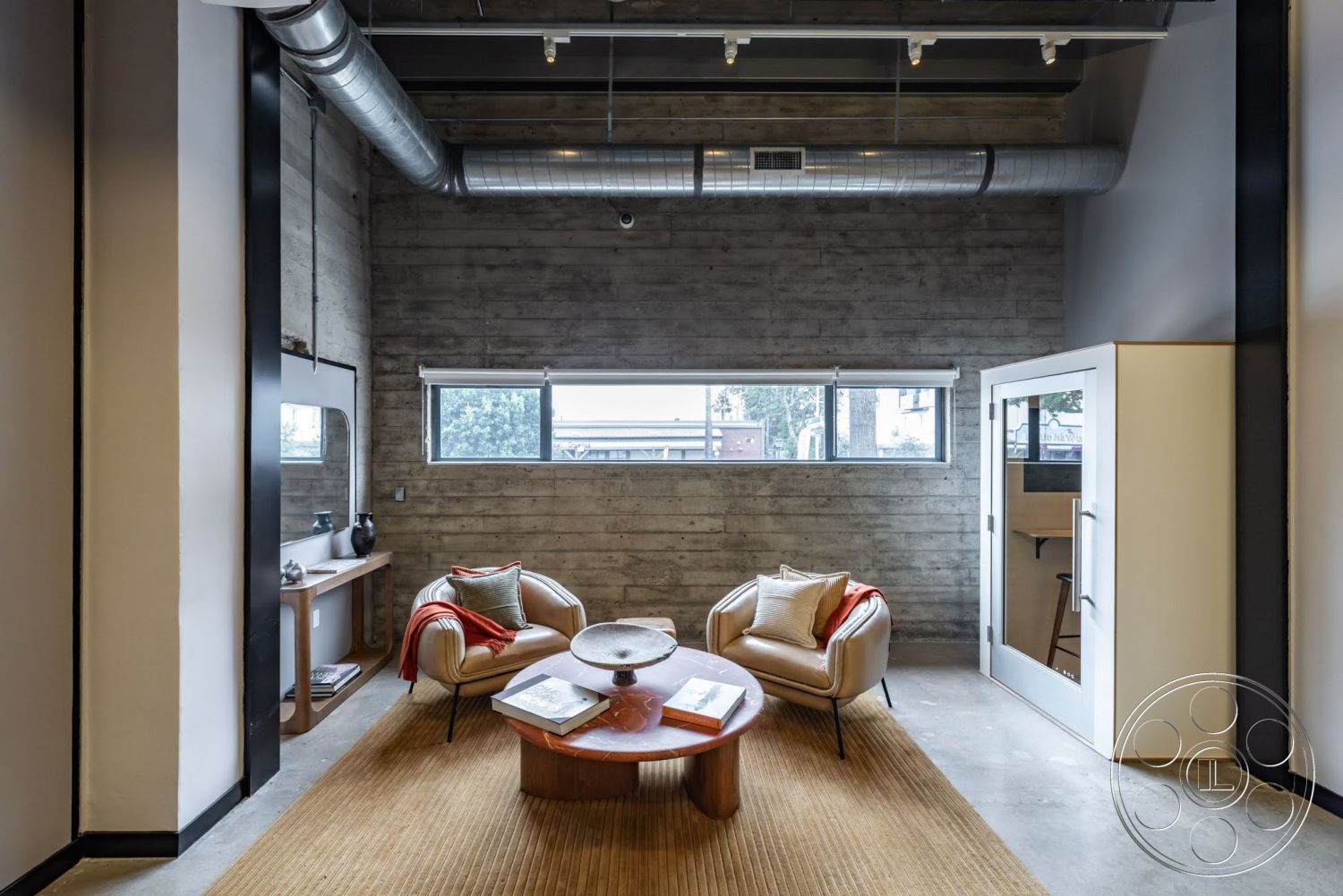 Sunset Campus - wood coffee table, textured area rug, concrete flooring, exposed concrete walls, floor-to-ceiling windows, metal ductwork ceiling, mid-century modern chair, glass meeting room