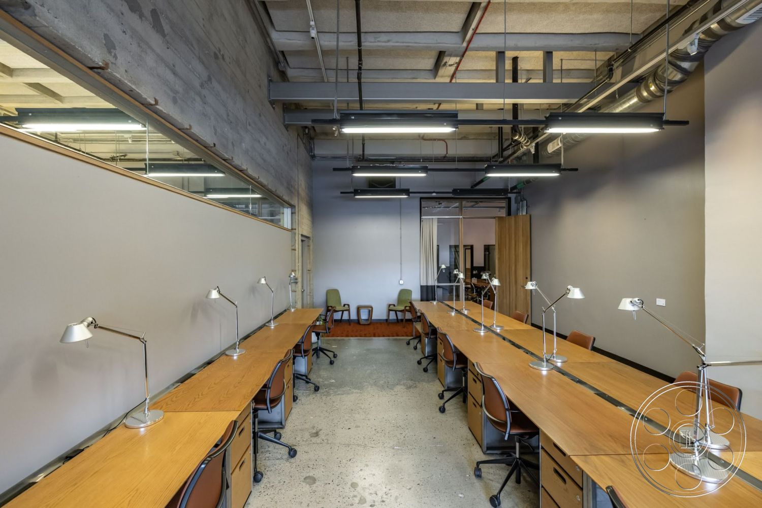 Sunset Campus - minimalist decor, polished concrete flooring, exposed concrete walls, glass partition walls, steel structural beams, open-plan office layout, industrial-style lighting fixtures, wooden office desks, textured gray walls, ceiling-mounted light fixtures, metal table lamps, brown leather office chairs