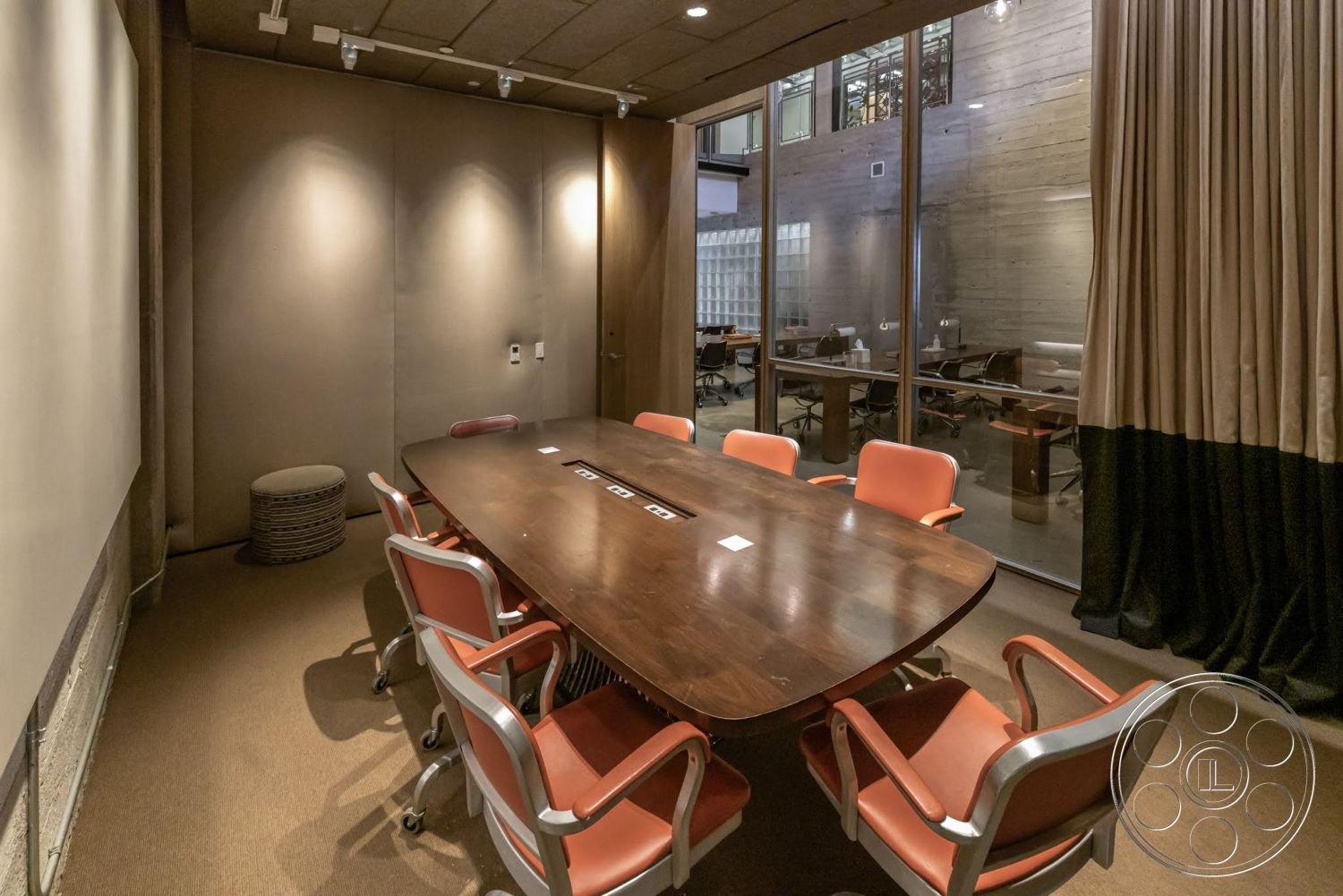 Sunset Campus - exposed concrete walls, carpet flooring, conference room, modern architectural style, acoustic ceiling tiles, metal framed chairs, floor-to-ceiling glass walls, wood conference table, textured fabric wall panels, curtained window treatments, orange seat cushions